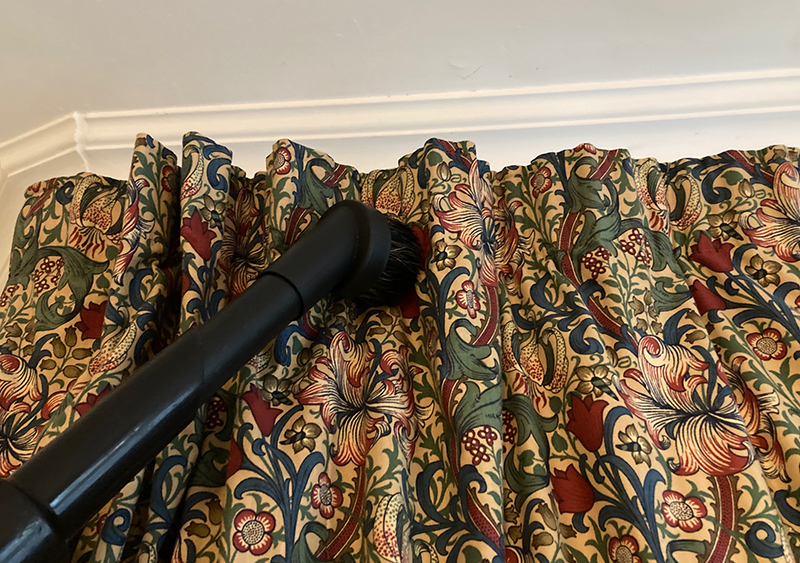 The Henry vacuum upholstery brush being used to vacuum curtains