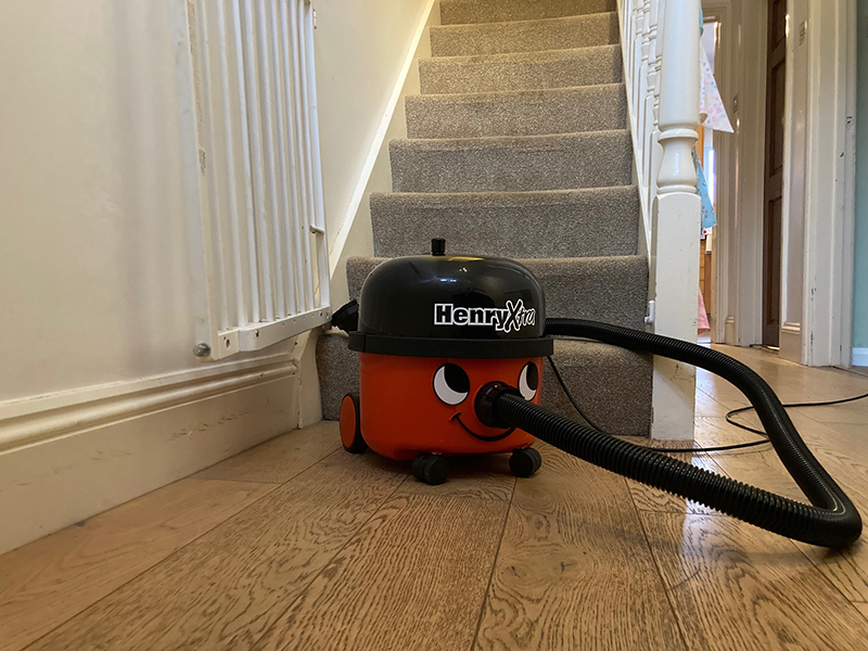 A Henry Xtra Vacuum Cleaner being used to clean a staircase.