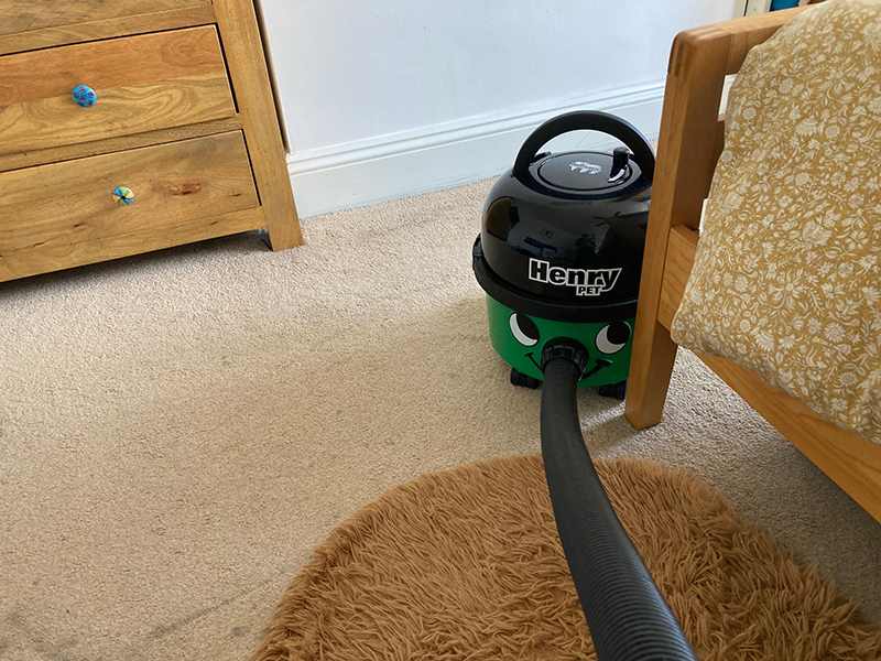 A Henry Pet vacuum cleaner bumping into furniture.