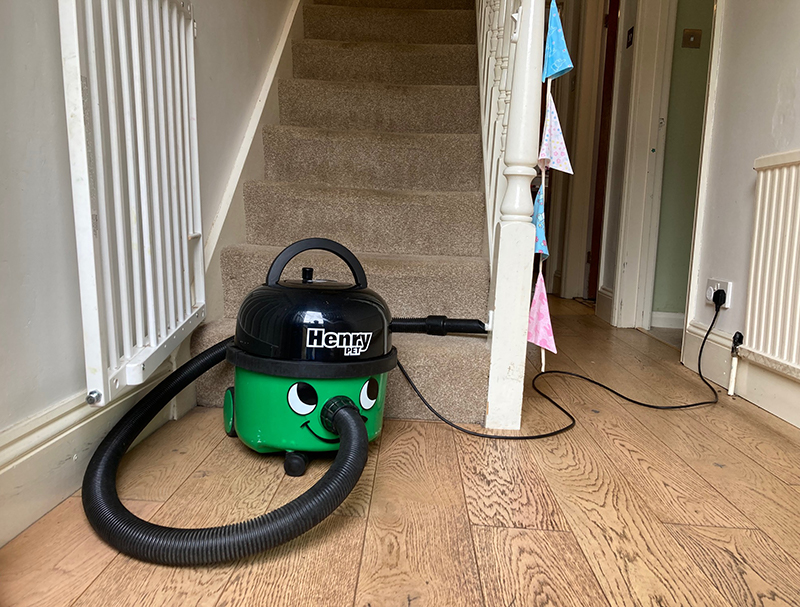 A Henry Pet vacuum cleaer at the bottom of a staircase.