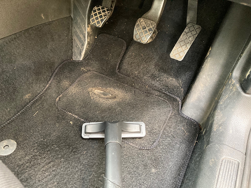 The upholstery brush attachment for the Henry Pet being used to vacuum a car mat.